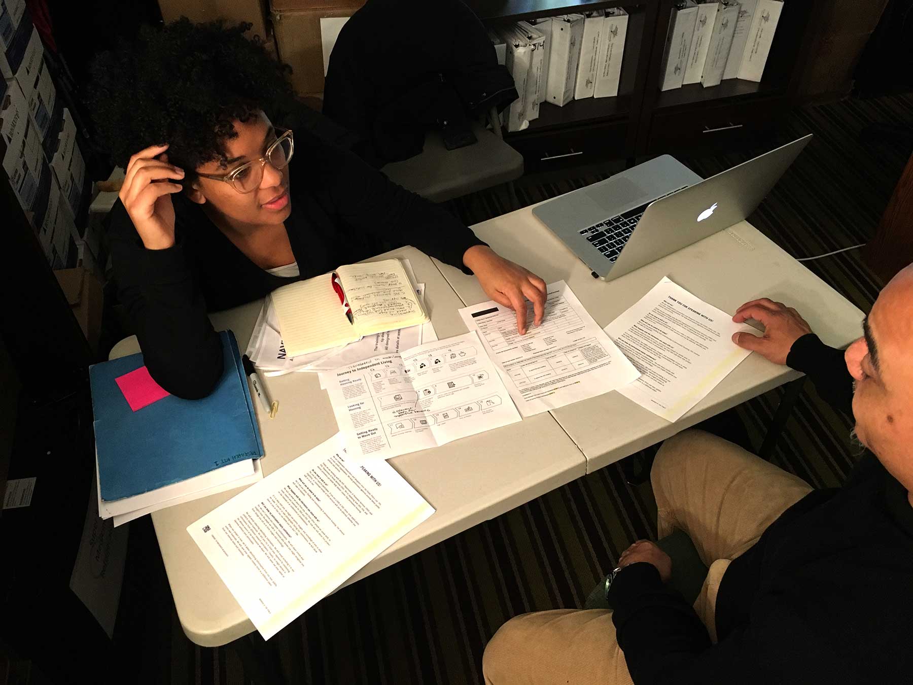 Two people review several documents at a table together.