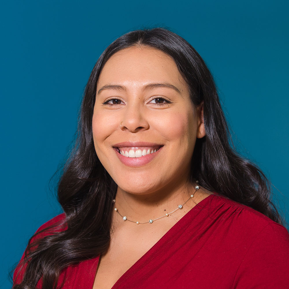 Headshot of Amanda Tommasino smiling in front of a dark blue background.