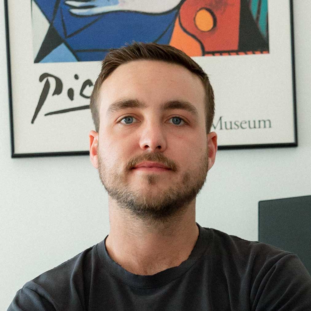 Headshot of Petey Routzahn in front of a colorful art poster.