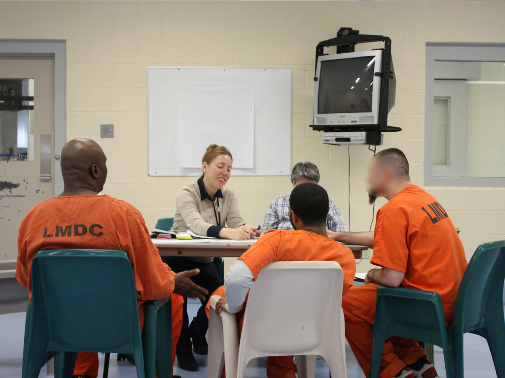 Two PPL team members have a conversation around a table with three incarcerated individuals at Louisville Metro Department of Corrections.