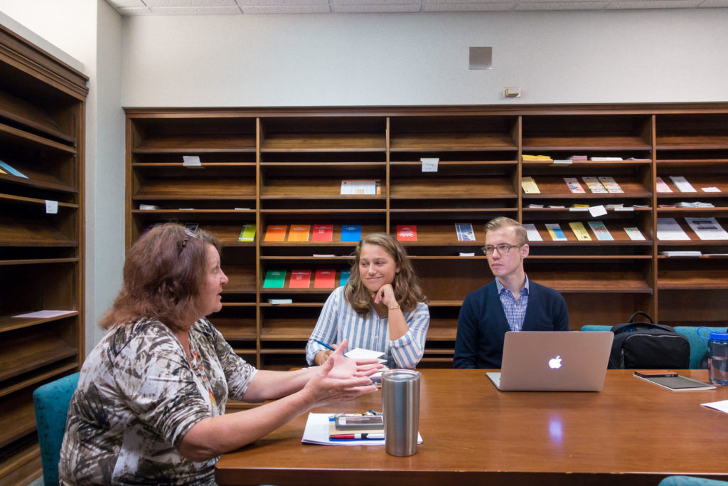 Three people talk together at a conference table while working on designing better experiences for veterans.