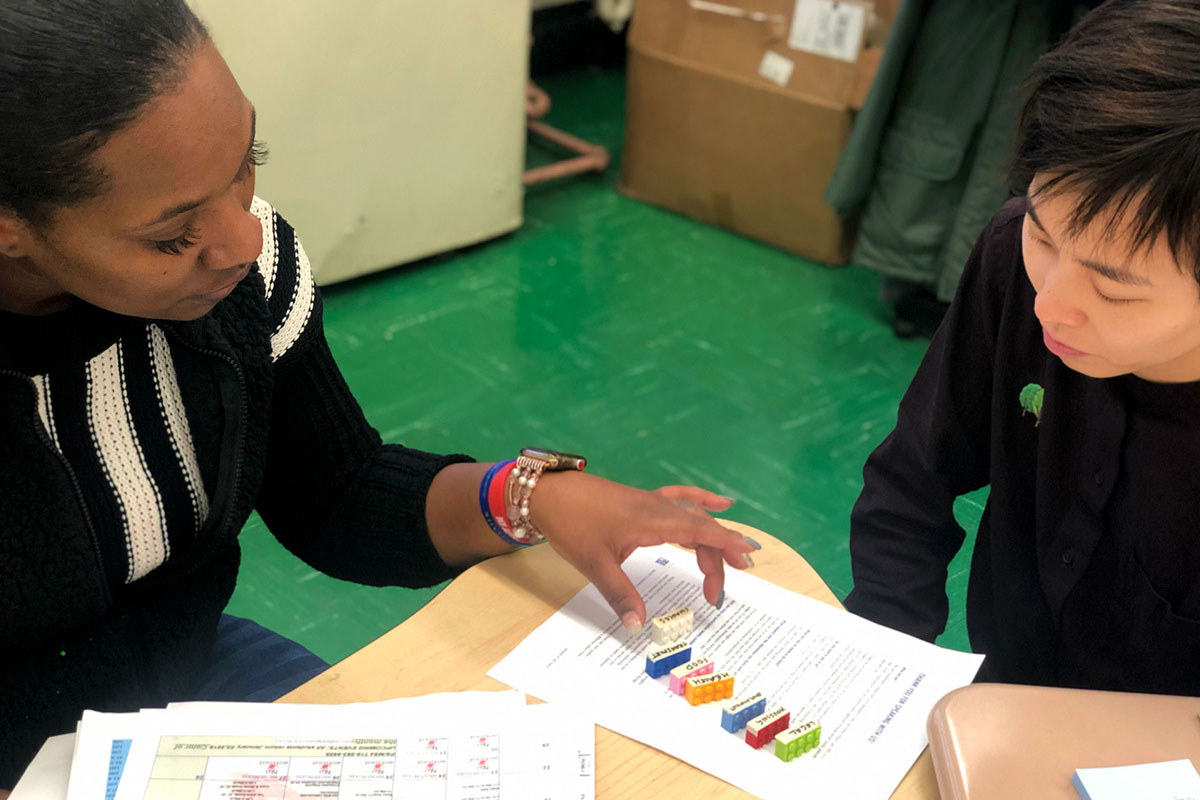 Two people sit together at a table interacting with a design activity.