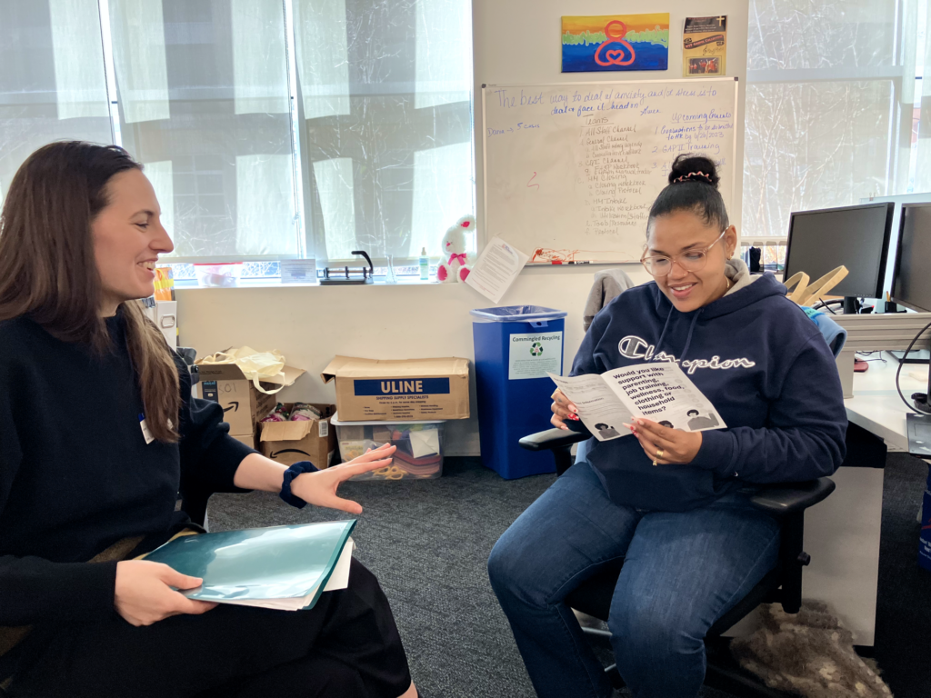 A researcher and a front-line staff have a conversation in the staff member's office. They look together a set of design stimuli.