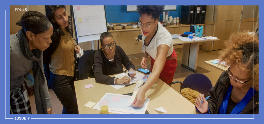 People standing around a table with papers and sticky notes.