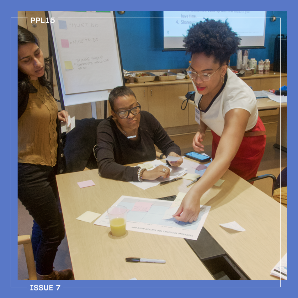 People standing around a table with papers and sticky notes.