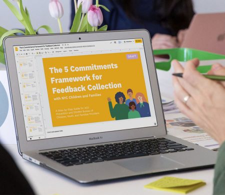 A presentation about the five commitments framework for feedback collection is pulled up on a laptop.