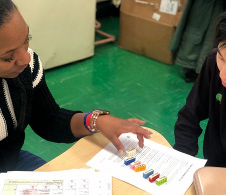 Two people sit together at a table interacting with a design activity.