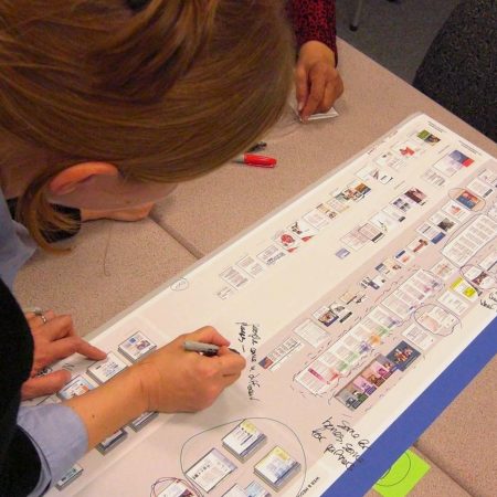 A PPL team member adds notes with a marker on a poster visualizing different communications channels in the Medicare system.